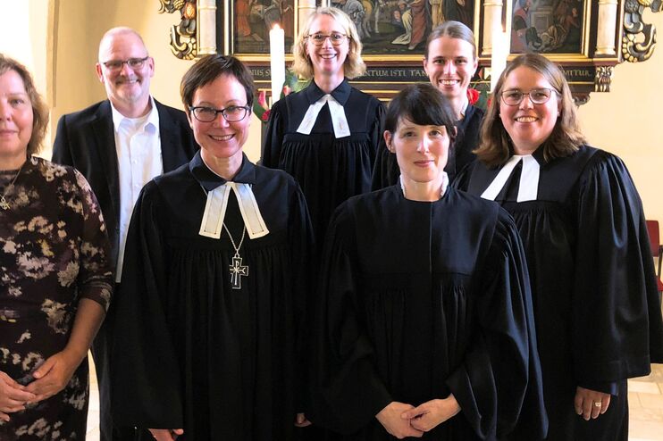 Eine Gruppe von Menschen in Talaren steht in einer Kirche.
