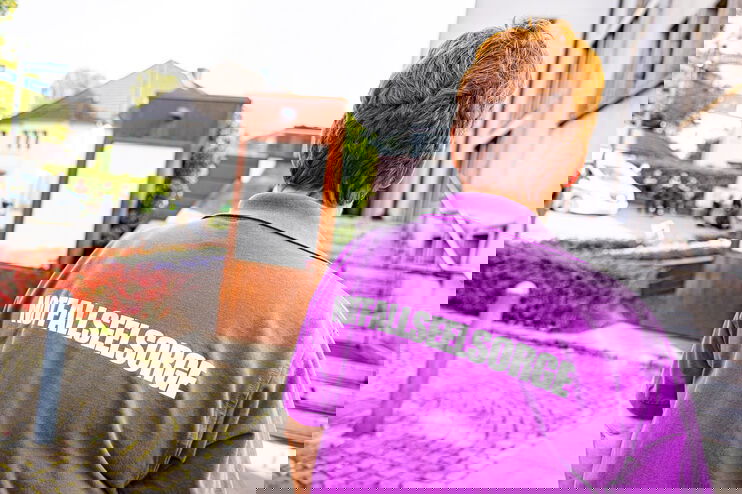 Eine weiblich gelesene Person mit einem pinkfarbenen T-Shirt, auf dem in weißen Buchstaben Notfallseelsorge steht.