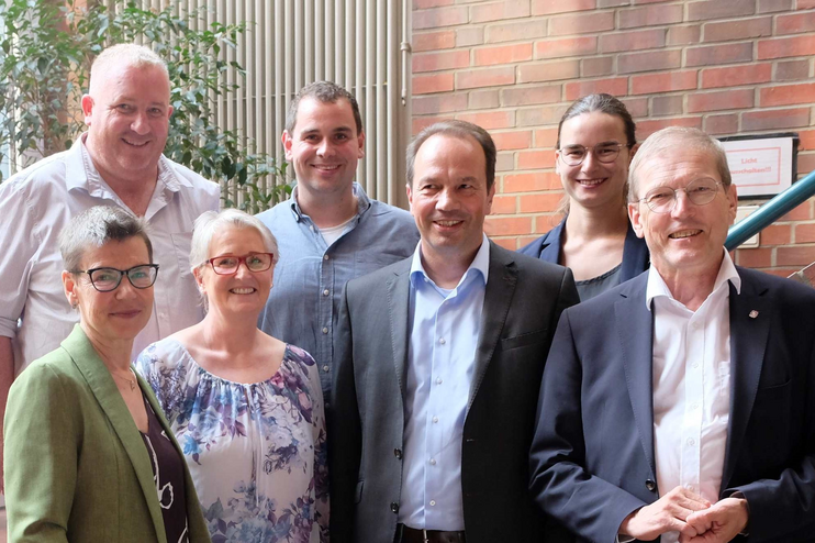 Mehrere Menschen stehen zusammen vor einigen Treppenstufen.