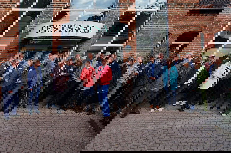 Eine Gruppe steht vor einem Gebäude mit dem Schild Festsaal.