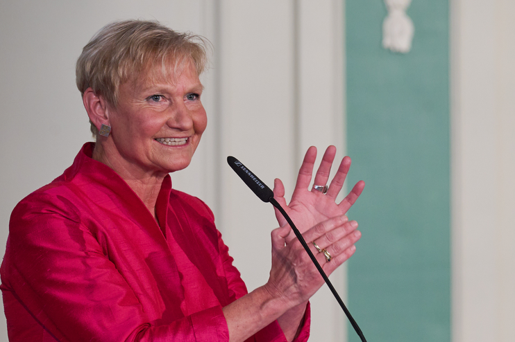 Eine weiblich gelesene Person in rotem Jackett steht vor einem Mikro an einem Redepult auf dem steht "EKD".