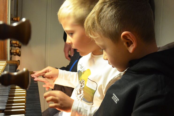 Zwei Grundschüler sitzen an einer Orgel und drücken die Tasten.