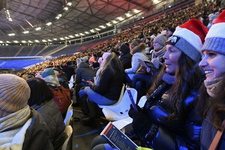 Menschen mit Weihnachtsmuetzen in einem Stadion