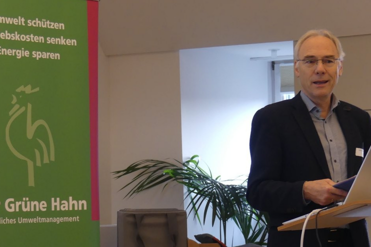 Ein Mann steht vor einem grünen Plakat.