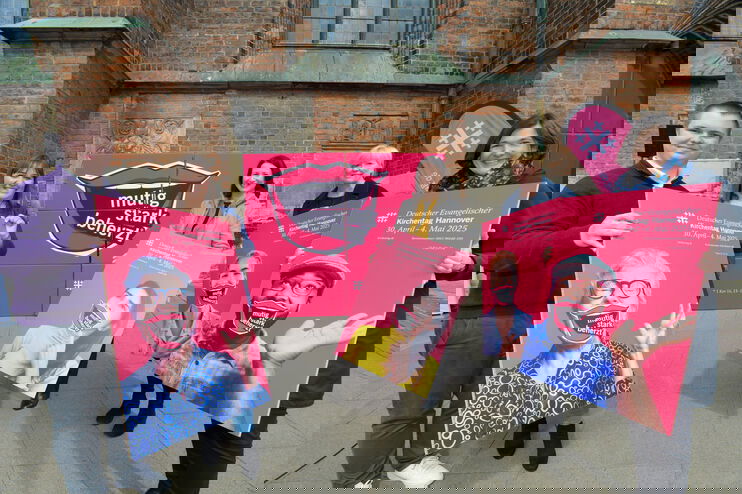 Mehrere Menschen, die rote Plakate präsentieren.