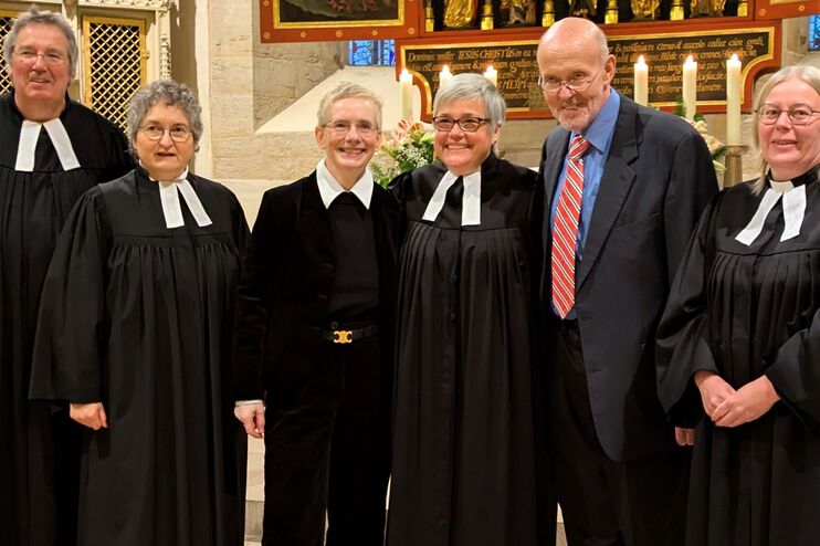 Menschen in Talaren vor einem Kirchaltar