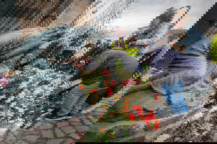 Viele Menschen legen Blumen am Eingang einer Kirche nieder.