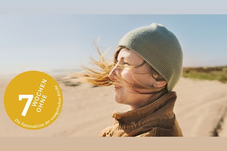 Eine weiblich gelesene Person mit Mütze steht am Strand oder in Dünen, der Wind treibt ihr die Haare ins Gesicht. Links unten steht in einem gelben Kreis: "7 Wochen ohne"