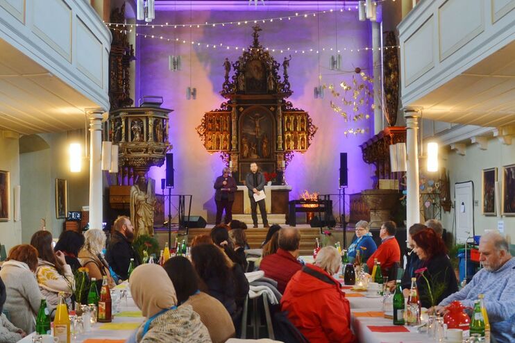 Menschen sitzen an Tischen in einer Kirche.