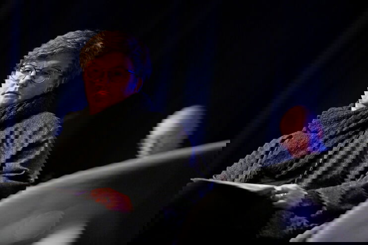 Eine Frau mit kurzen Haaren vor einem dunklen Hintergrund.