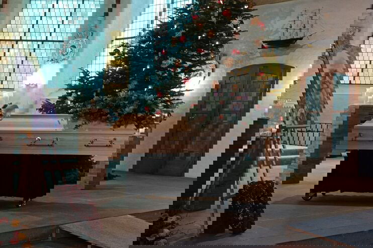 Ein Sarg steht vor einem Weihnachtsbaum in einer Kirche. 