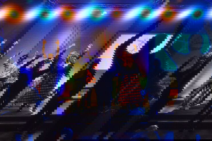 Menschen stehen auf einer Bühne und tanzen. 