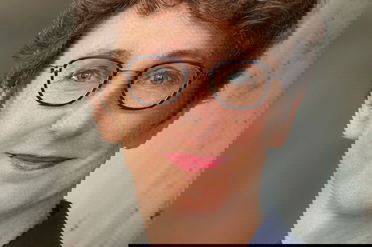 Eine als Frau lesbare Person mit Brille und kurzen lockigen Haaren.