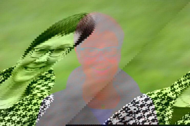 Eine als Frau lesbare Person mit kurzen Haaren und Brille.