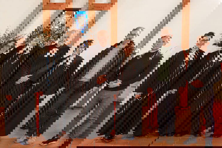 Eine Gruppe aus weiblich und männlich lesbaren Personen posiert im Talar.