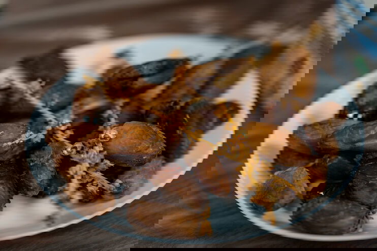 Auf einem weißen Teller liegen Datteln.