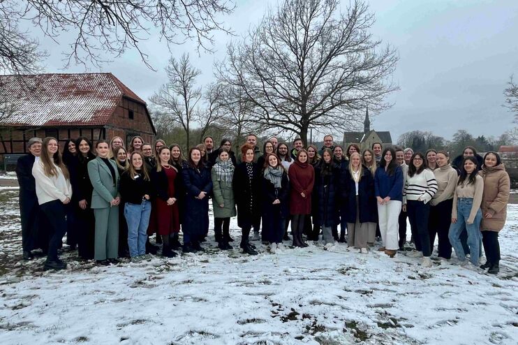 Mehrere Menschen stehen auf einer verschneiten Fläche, im Hintergrund ein spitzer Kirchturm vom Kloster Loccum.