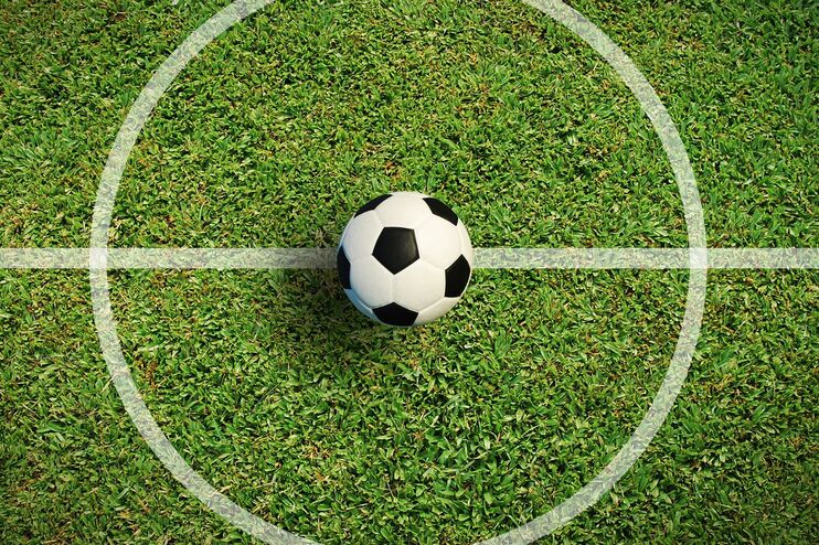 Ein Fußball auf der Mittellinie auf einem Fußballfeld.