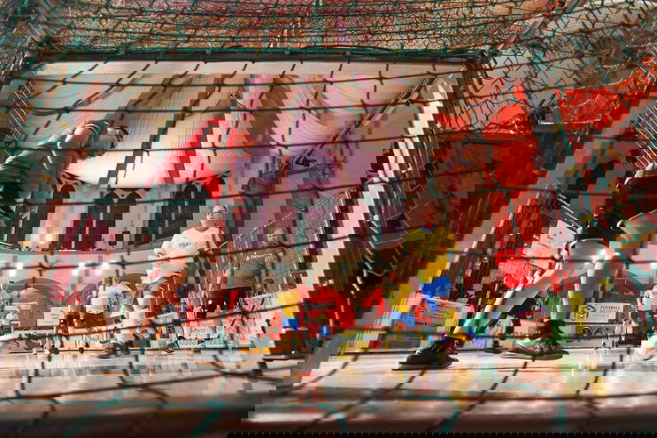 In einer Kirche spielen als Männer lesbare Personen auf einem Indoor-Feld Fußball.