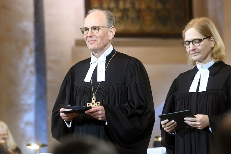 Ein Mann und eine Frau stehen im Talar vor einem Altar.