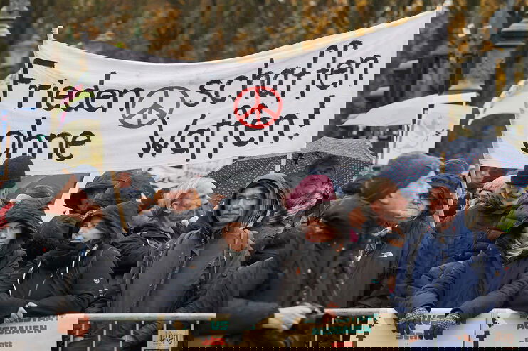 Demonstrierende halten ein Transparent mit der Aufschrift "Frieden schaffen ohne Waffen hoch".