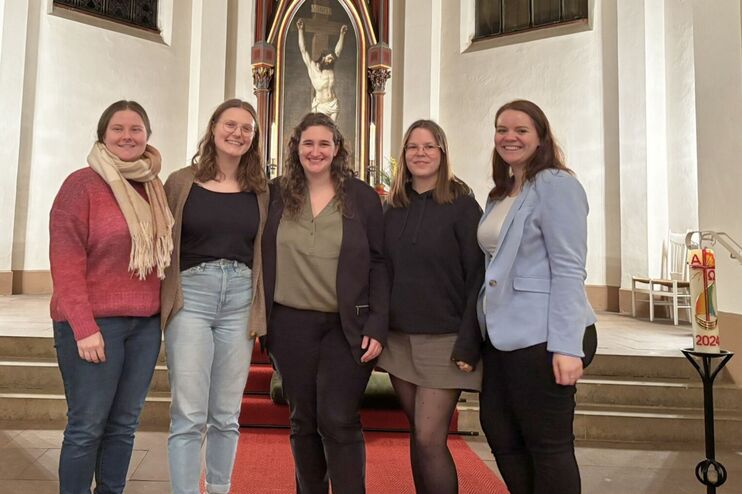 Fünf Frauen stehen lächelnd vor einem Altar.