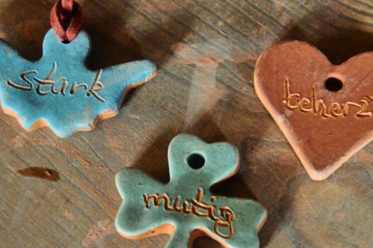 Drei Anhänger aus Ton, in Form eines Engels, Kleeblatts und Herzens. Darin steht mutig, stark und beherzt.