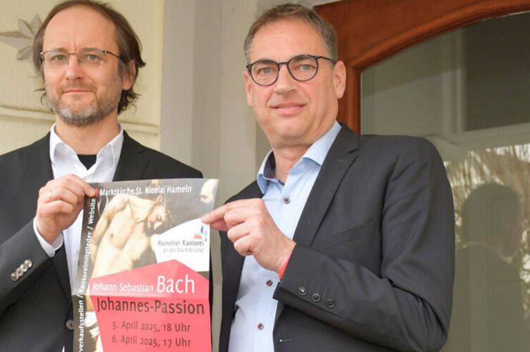 zwei Männer halten ein Plakat in der Hand und stehen vor einem Gebäude.