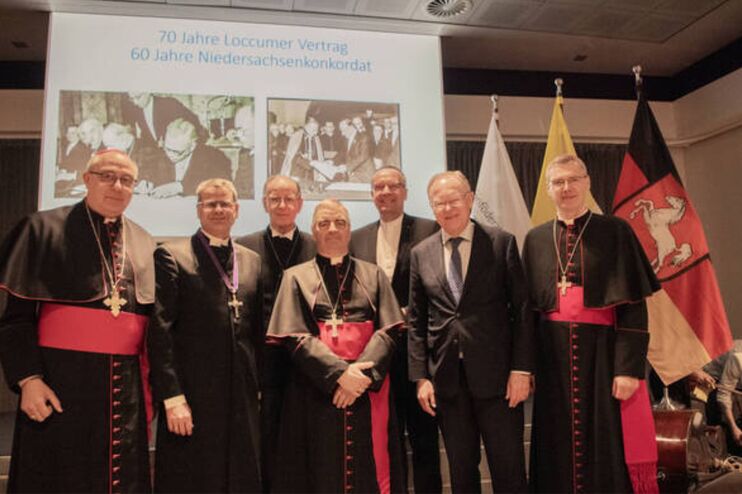 Eine Gruppe Männer in festlicher Kleidung wird auf einer Bühne fotografiert.