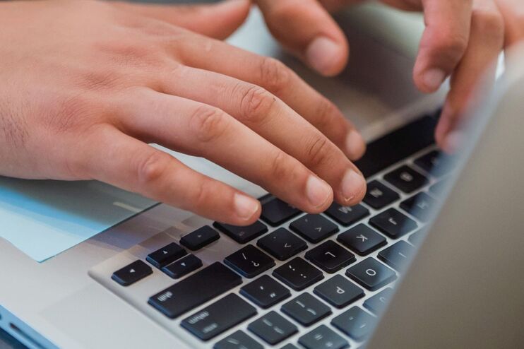 Hände tippen auf einer Computertastatur.
