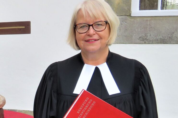 Eine Frau im Talar mit einem roten Buch.