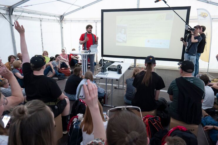 Menschen in einem Zelt melden sich und diskutiert.