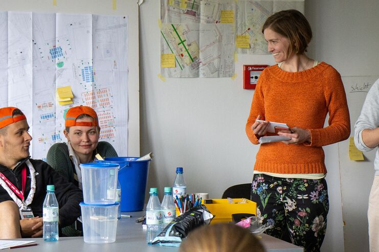 eine Gruppe von Menschen in einem Raum unterhaelt sich