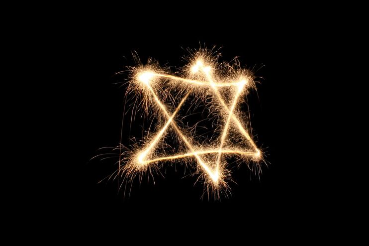 Ein gold-funkelnder jüdischer Stern im Dunkel.