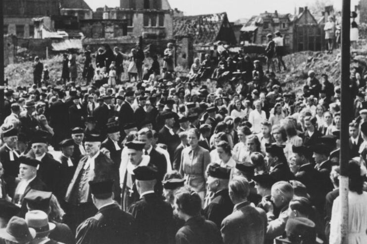 Geistliche ziehen, umringt von Menschen, durch eine zerstörte Stadt (Hannover).