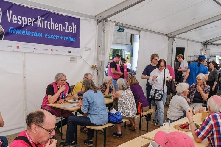 Menschen sitzen in einem Zelt und essen.