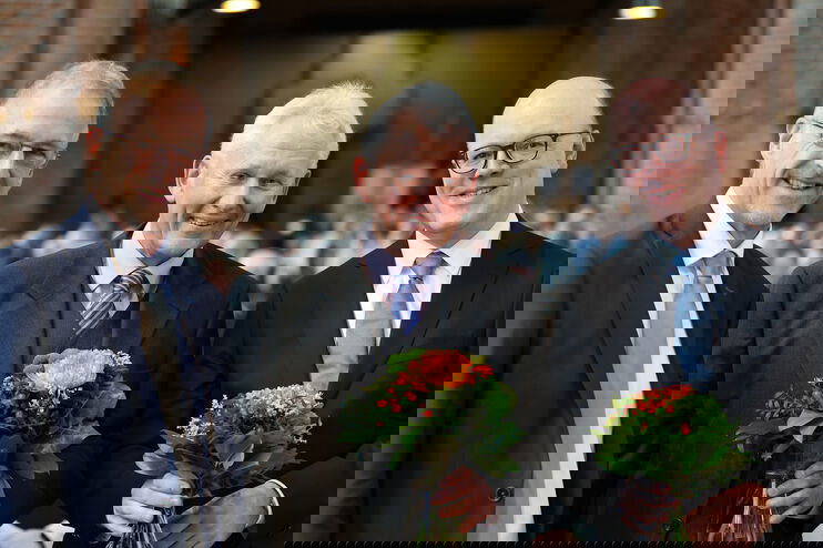 Drei männlich zu lesende Person stehen nebeneinander und lächeln.