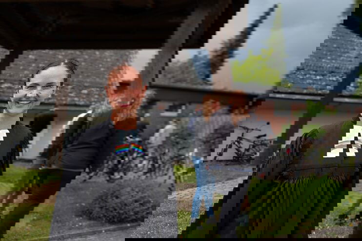 Eine weiblich gelesene Person im Talar steht im Freien und lächelt.