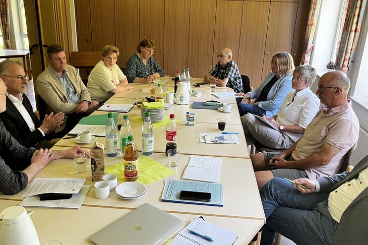 An einem langen Tisch sitzt ein Dutzend Menschen und diskutiert miteinander. 