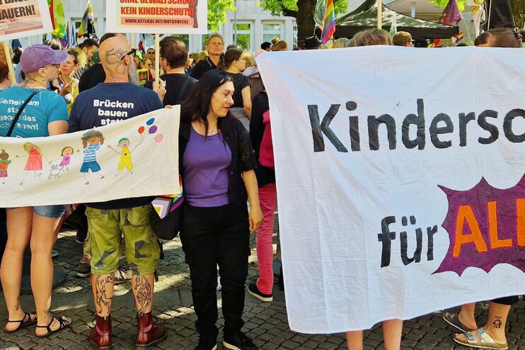 Menschen auf einer Demonstration mit einem Banner, darauf steht Kinderschutz für alle.