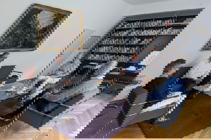 Vier Personen sitzen rund um einen niedrigen Tisch im Gespräch. 