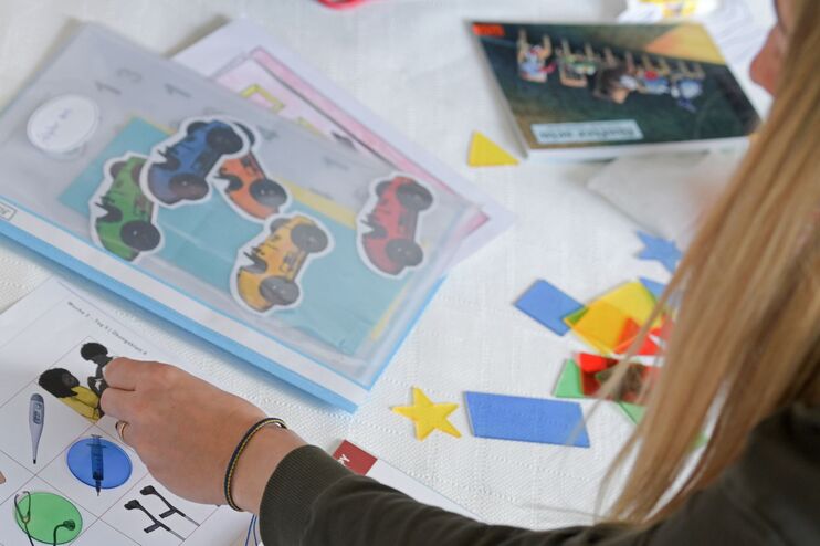 Ein Frau beugt sich über bunte Arbeitsblätter. 