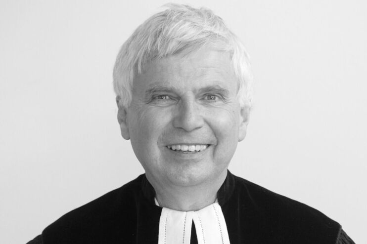 Ein Schwarzweißbild einer als Mann lesbaren Person im Talar.