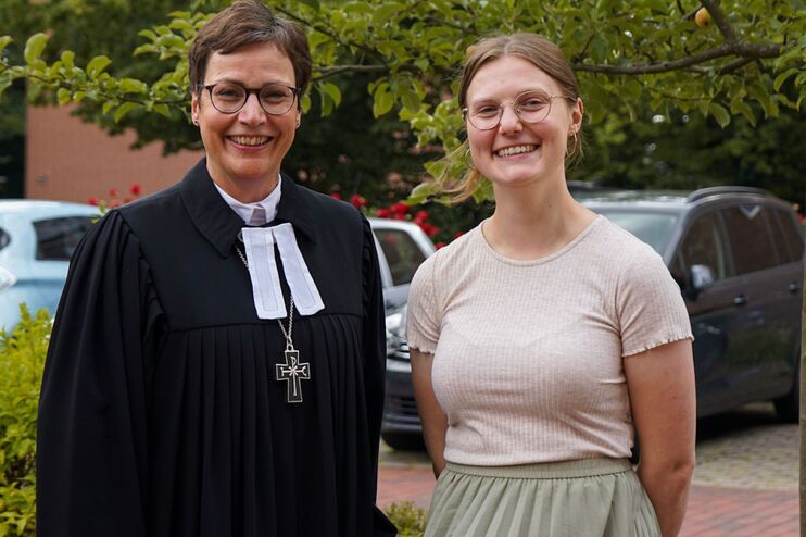 Zwei Frauen lächeln, eine trägt einen Talar.