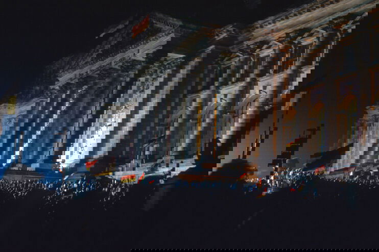 Viele Menschen im Dunkeln vor dem Brandenburger Tor, mit Deutschlandfahnen.