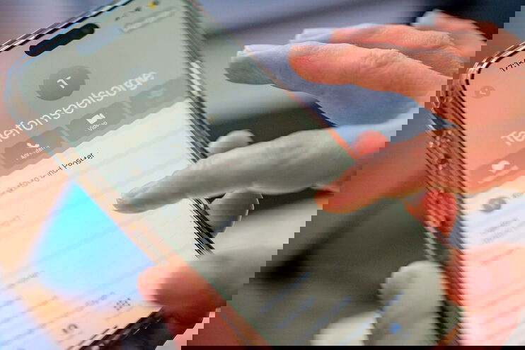 Eine Person wählt auf einem Smartphone die Nummer der Telefonseelsorge.