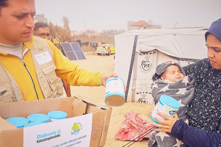 Ein Mann reicht einer verschleierten Frau Lebensmittel.