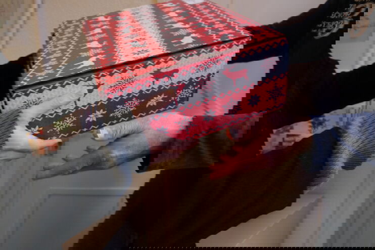 Ein Paket wird von einer zu einer anderen Person übergeben.