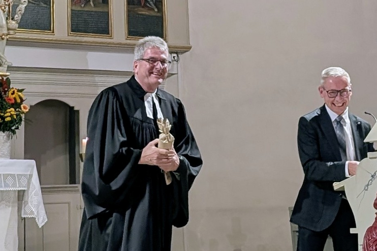 Zwei männlich gelesene Personen in Talaren in einer Kirche.