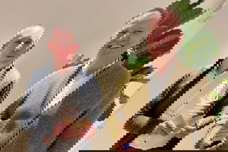 Zwei als Männer lesbare Personen mit Trophäen in der Hand.